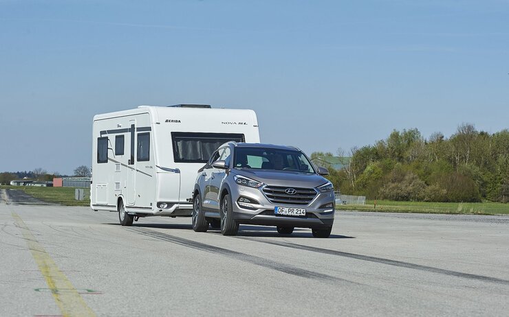ÖAMTC Vergleich - SUV als Zugfahrzeuge Ein SUV fährt auf einer Teststrecke mit einem Wohnwagen-Anhänger.