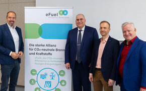 Vier Männer im Anzug bei einer Präsentation