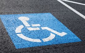 Behindertenparkplatz Behindertenparkplatz mit einem blau/weißen Rollstuhlpiktogramm auf Straßenasphalt.