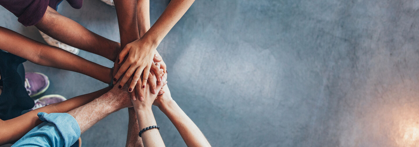 Konsumentenschutz Eine Gruppe von Personen steht zusammen und hält sich an den Händen.